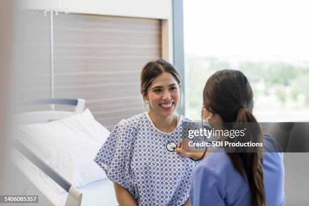 junge erwachsene frau lächelt den kardiologen an - pregnant woman at doctor stock-fotos und bilder