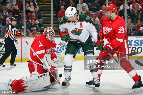 Jimmy Howard of the Detroit Red Wings makes a save as teammate Brad Stuart battles for the rebound with Matt Cullen of the Minnesota Wild during a...