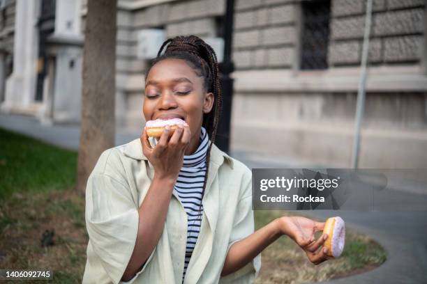 giovane donna africana positiva - eating donuts foto e immagini stock