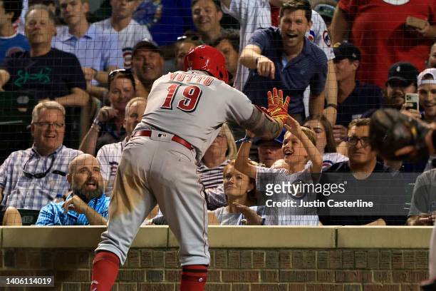 Joey Votto of the Cincinnati Reds high fives a Chicago Cubs fan after hitting a home run during the sixth inning at Wrigley Field on June 30, 2022 in...
