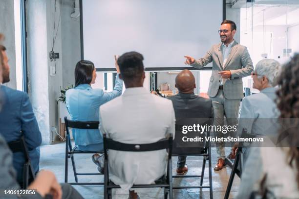 homme d’affaires parlant à un groupe de personnes dans une salle de conférence. - discours-liminaire photos et images de collection