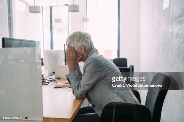 overworked mature businesswoman in the office. - fish out of water stock pictures, royalty-free photos & images