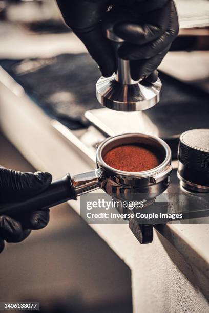 closeup barista hands using a tamper to press ground coffee into a portafilter - coffee powder stock-fotos und bilder