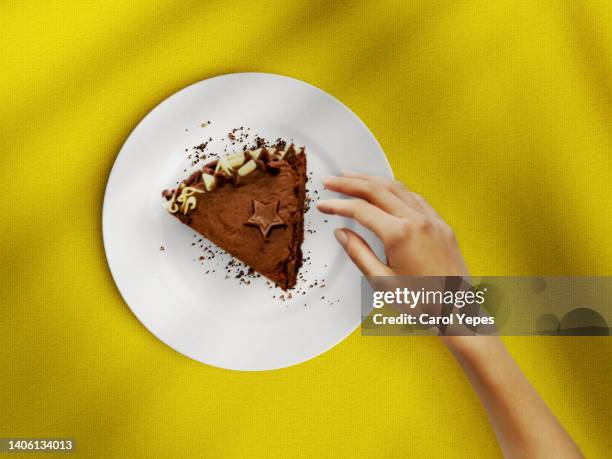 female hand reach for a piece of chocolate cake on plate.top view - chocolate top view imagens e fotografias de stock