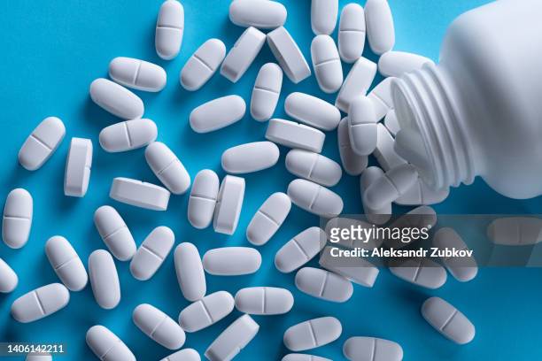 white capsules and tablets on a blue background. taking vitamins, painkillers, medications, and dietary supplements. the concept of pharmaceuticals, prevention and treatment of diseases, healthcare and medicine. pregnancy planning, filling the deficit. - slaappil stockfoto's en -beelden