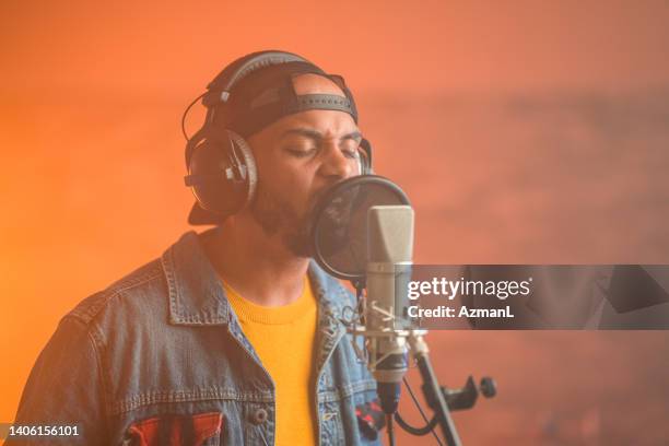 young hip hop singer recording music in recording studio - rap singer stock pictures, royalty-free photos & images