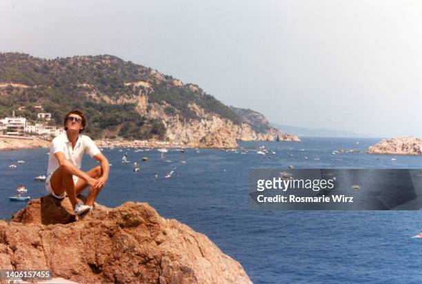 palau beach: young italian on rock enjoying sun - famous 80's fashion clothes stock-fotos und bilder
