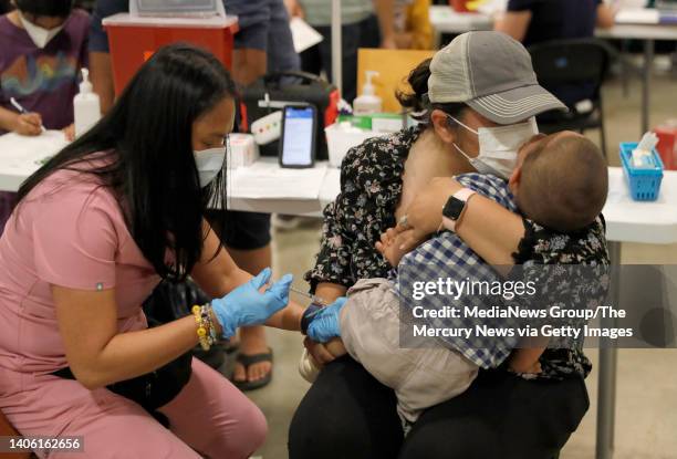 Namrata Nayyar, left center, kisses her son Ari Dawra, 18 months, as he receives his Covid-19 vaccination from licensed vocational nurse Jacqueline...