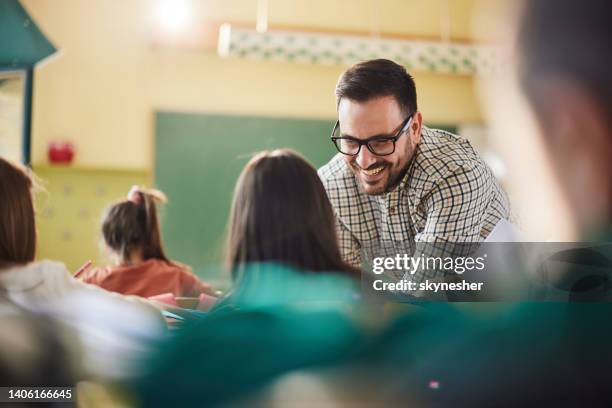 glücklicher professor, der schulmädchen in einer klasse in der schule unterstützt. - elementary school building stock-fotos und bilder