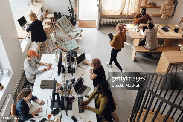 high angle view of male and female entrepreneurs working at tech start-up office - start up office imagens e fotografias de stock