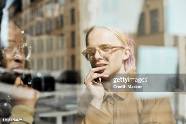 business colleagues discussing while looking at adhesive note on glass window in office - nonbinary stock pictures, royalty-free photos & images