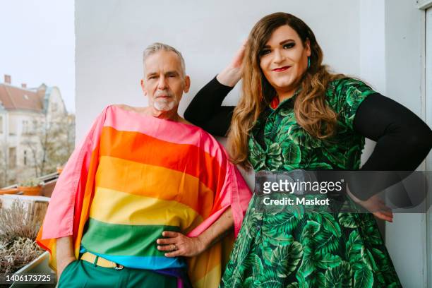 portrait of mature gay man standing by non-binary friend on balcony - body positive men stock pictures, royalty-free photos & images