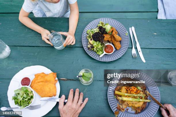 family lunch  on garden table. schnitzel, asparagus and salad - schnitzel stockfoto's en -beelden