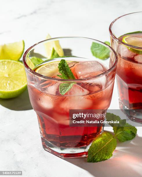 fresh summer strawberry, lime and mint cocktail with ice cubes closeup, vertical. drinking glass of soda drink. cold lemonade recipe. vitamin ready-to-eat delicious mojito. sunlight, white marble background - glass marble imagens e fotografias de stock