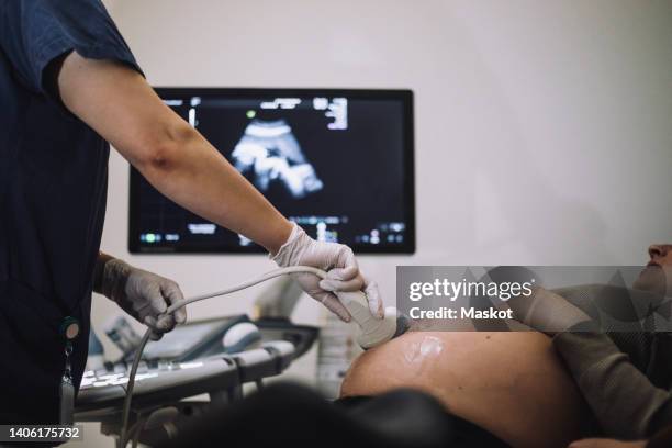 female gynecologist doing ultrasound of pregnant woman in hospital - ultrasound scan stock-fotos und bilder