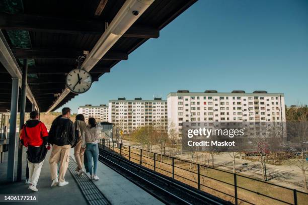 rear view of multiracial friends walking on railroad station platform - quai de gare photos et images de collection
