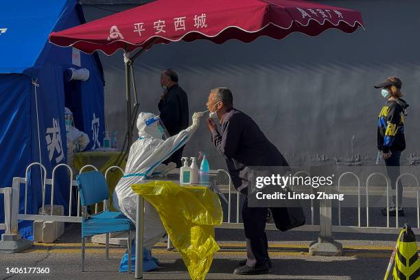 Person takes a swab test at a COVID-19 test site on June 30, 2022 in Beijing, China. China is trying to contain a spike in coronavirus cases in the...