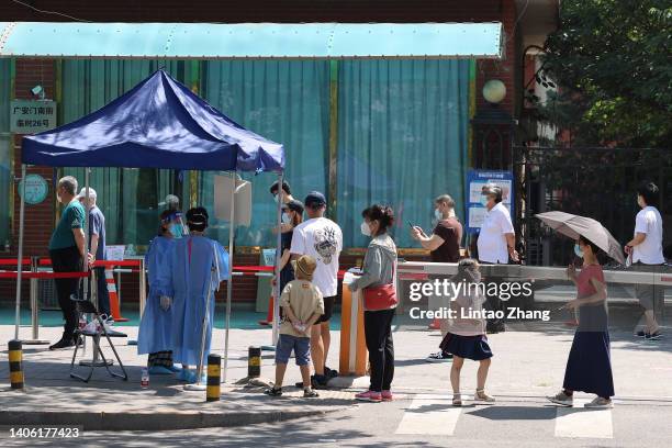 People wait in line for a swab test at a COVID-19 test site on June 30, 2022 in Beijing, China. China is trying to contain a spike in coronavirus...