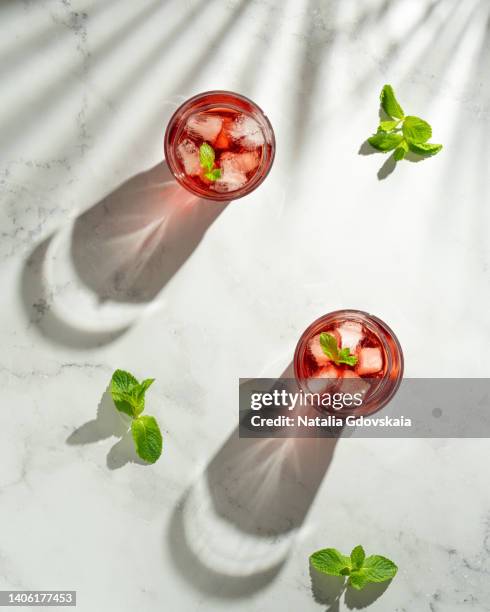 fresh summer strawberry, lime and mint cocktail with ice cubes. drinking glass of soda drink. cold lemonade recipe. two glasses of vitamin ready-to-eat mojito. table top view, vertical, sunlight, white marble background, copy space - cocktail recipe stock pictures, royalty-free photos & images