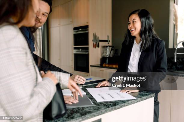 smiling real estate agent explaining documents of new house to customers - real estate agent stock pictures, royalty-free photos & images