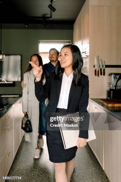 real estate agent pointing while showing kitchen area to customers at new house - real estate agent imagens e fotografias de stock