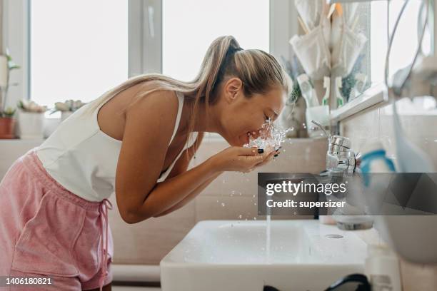 i need a splash of water - woman washing face stockfoto's en -beelden