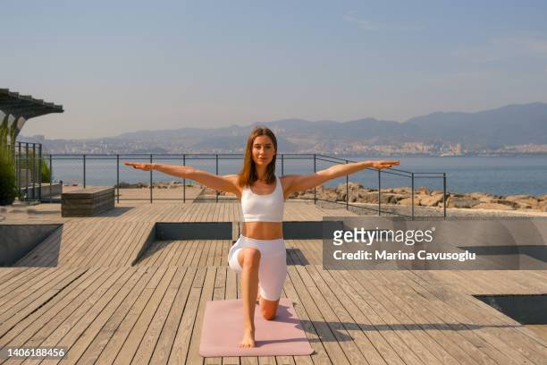 young woman doing yoga exercise at the sea. - one embankment stock-fotos und bilder