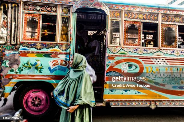 a pakistani woman is getting off a colourful bus in karachi. sindh, pakistan - burka stock pictures, royalty-free photos & images