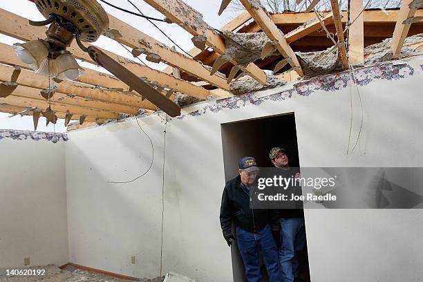 Mike Reilmann and his son, Mike Reilmann, inspect the home of the father's mother after it was hit by a tornado that passed through the town on March...