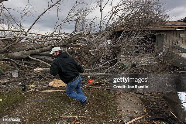Mathew Bailey pulls tree branches off of a relative's home, which was damaged by a tornado that passed through the town on March 3, 2012 in Holton,...