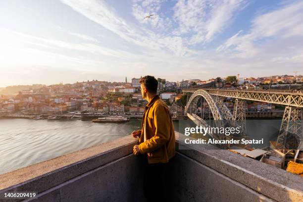 man enjoying sunset above porto town with view of douro river and dom luis i bridge, portugal - porto portugal stock-fotos und bilder