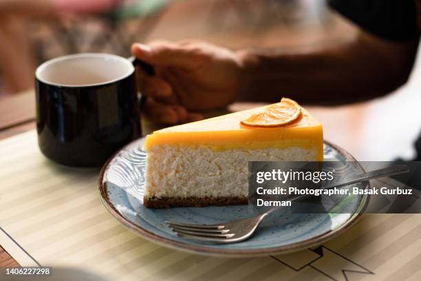 a man eating a slice of lemon cheesecake and drinking coffee - cheesecake stock pictures, royalty-free photos & images