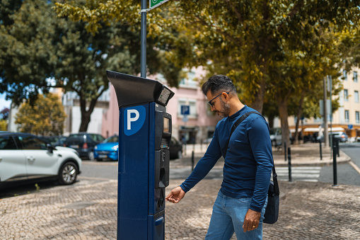 Man pays for parking with coin in a special pay machine in Lisbon, Portugal