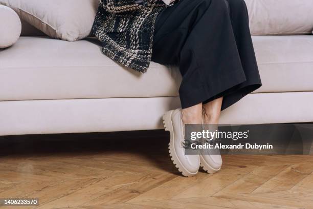 woman sitting on the sofa. women's legs in shoes and pants close-up copy space. - beautiful legs in high heels stock-fotos und bilder