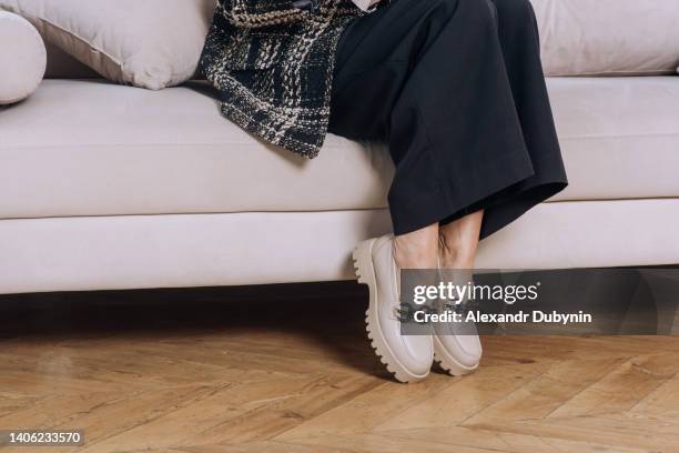 woman sitting on the sofa. women's legs in shoes and pants close-up copy space. - female foot models ストックフォトと画像