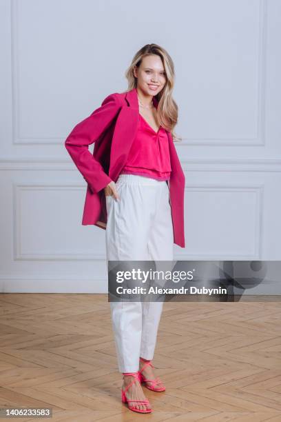 happy blonde woman standing studio shot - pink jacket stock pictures, royalty-free photos & images