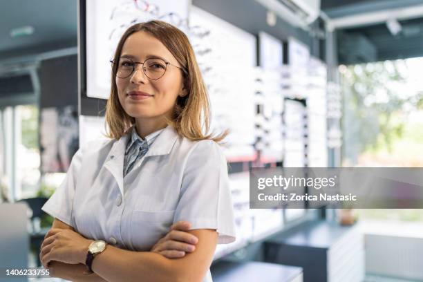 optician looking at the camera smiling in optical store - optisch instrument stockfoto's en -beelden