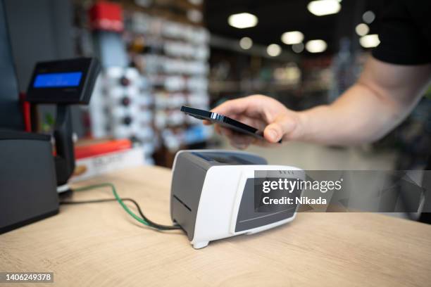 jeune homme effectuant un paiement dans un magasin de vélos - magasin de sport photos et images de collection