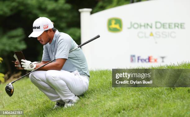 Satoshi Kodaira of Japan checks his scorecard on the 17th tee during the second round of the John Deere Classic at TPC Deere Run on July 01, 2022 in...