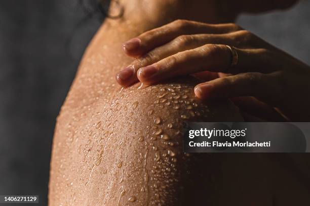 woman's shoulder with hand on shower - hand washing stockfoto's en -beelden