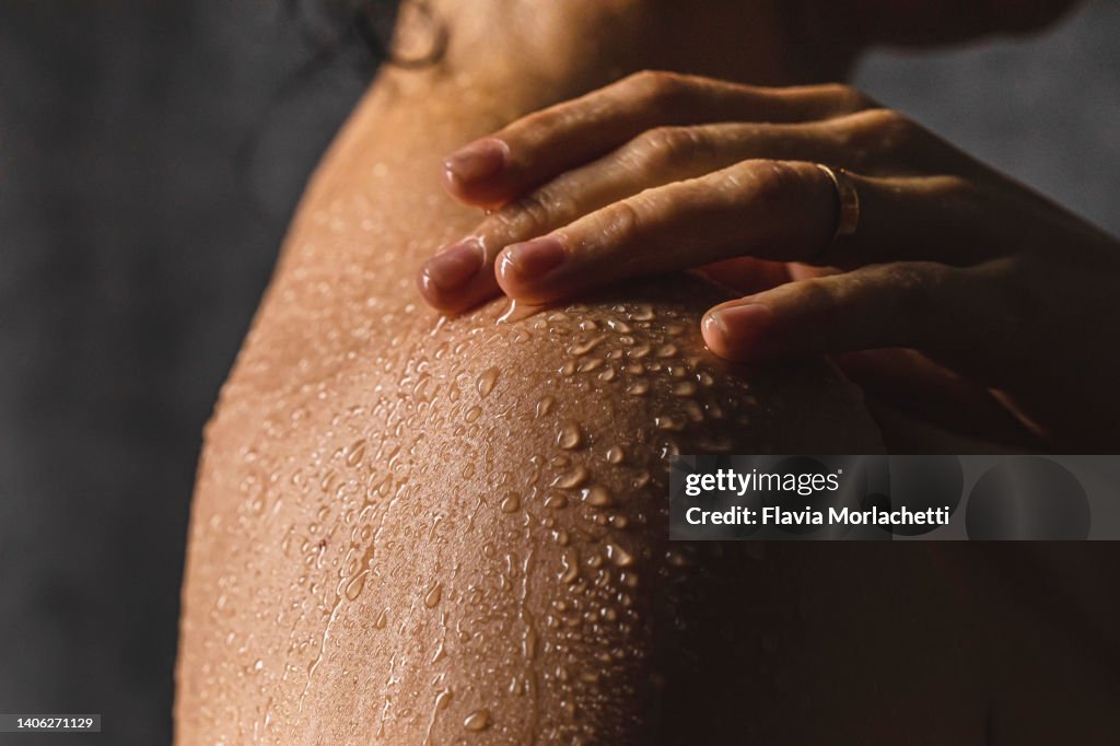Woman's shoulder with hand on shower