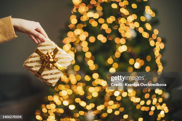 photo of luxury gift boxes under christmas tree, new year home decorations, golden wrapping of santa presents, festive tree decorated with garland, baubles, traditional celebration. copy space - christmas presents under tree stock pictures, royalty-free photos & images