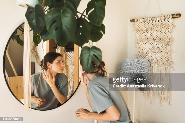 woman looking in the mirror in a cozy interior. - macrame stock pictures, royalty-free photos & images