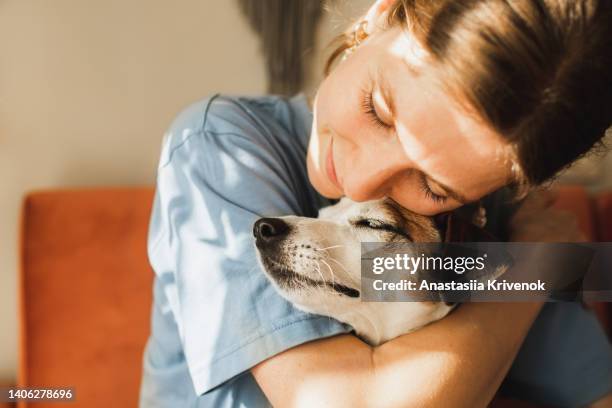 cute young woman playing and hugging her jack russell terrier dog. - animals hugging stock-fotos und bilder