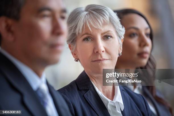 portrait of senior caucasian businesswoman with multiracial colleagues at meeting - grey hair stress stock pictures, royalty-free photos & images