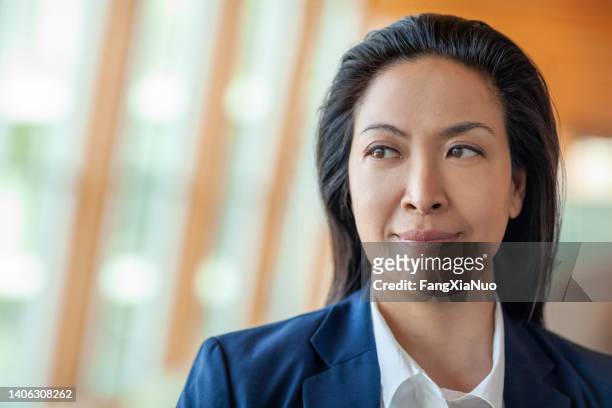 portrait of chinese businesswoman looking away at office lobby - political uncertainty stock pictures, royalty-free photos & images