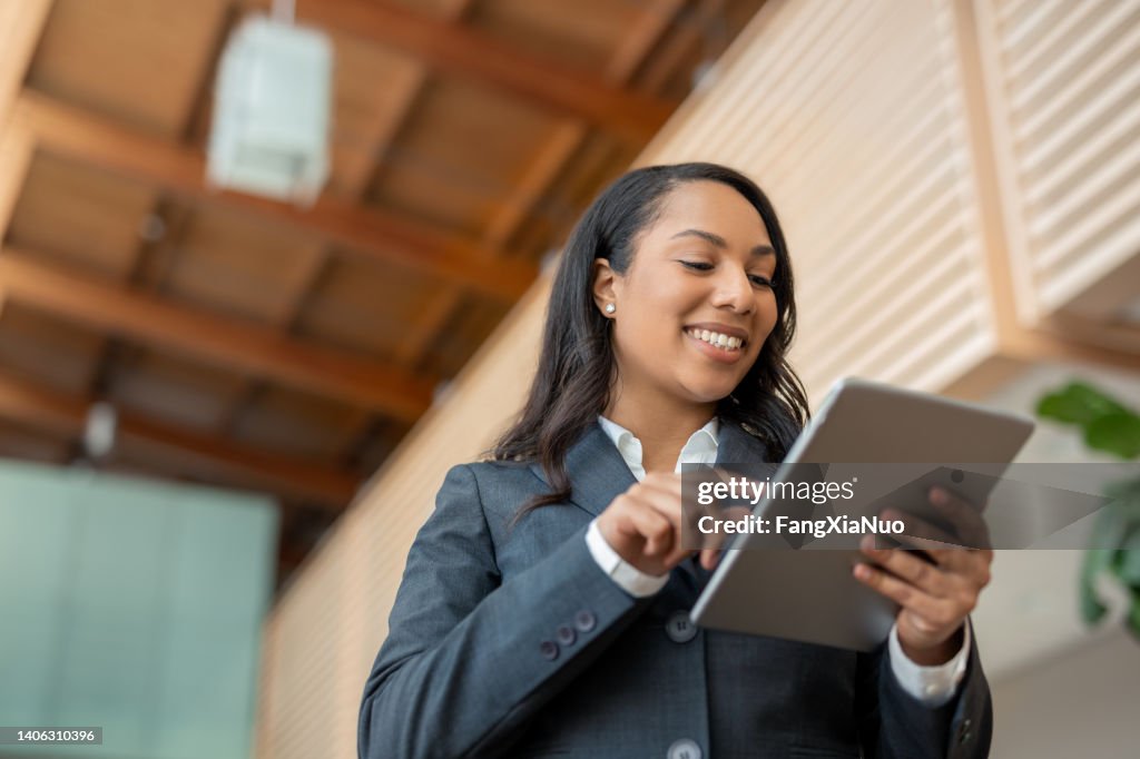 Portrait of multiracial African American Black businesswoman using internet with digital tablet low angle view