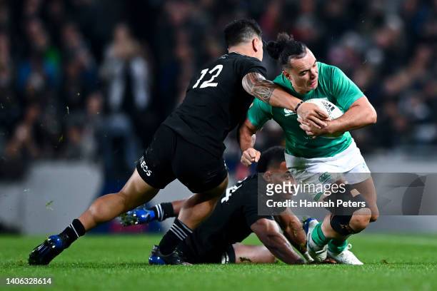James Lowe of Ireland is tackled by Quinn Tupaea and Sevu Reece of New Zealand during the International test Match in the series between the New...