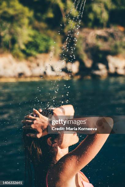 woman taking shower close up. outdoors shower after beach day. - taking a shower at the beach stockfoto's en -beelden