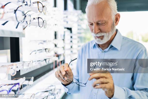 uomo anziano che prova gli occhiali da vista - occhiali da lettura foto e immagini stock